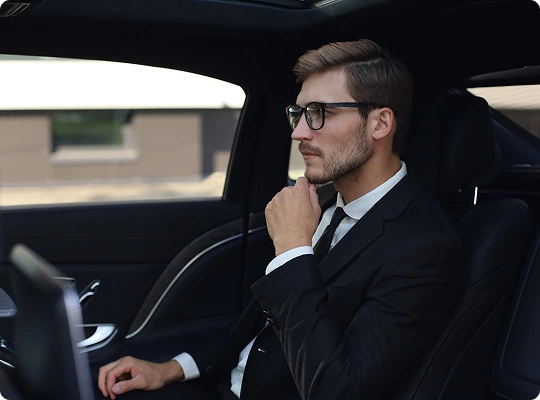 Stylish businessman in a sharp suit sits thoughtfully in the backseat of a high-end luxury car—surrounded by premium interior finishes, capturing the essence of executive travel and quiet confidence.