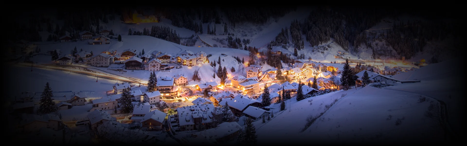 Aerial view of a snow-blanketed Aspen village glowing with warm lights at dusk—highlighting the enchanting winter charm and scenic elegance along the Denver to Aspen journey.