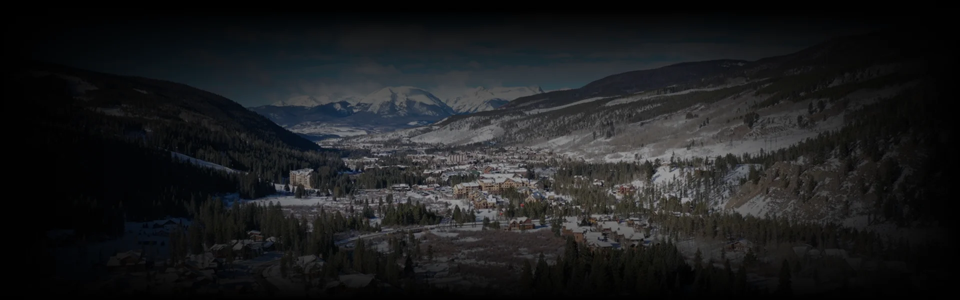 Snow-covered alpine village nestled among pine-covered hills and towering peaks—showcasing the breathtaking winter landscape along the Denver to Beaver Creek route.