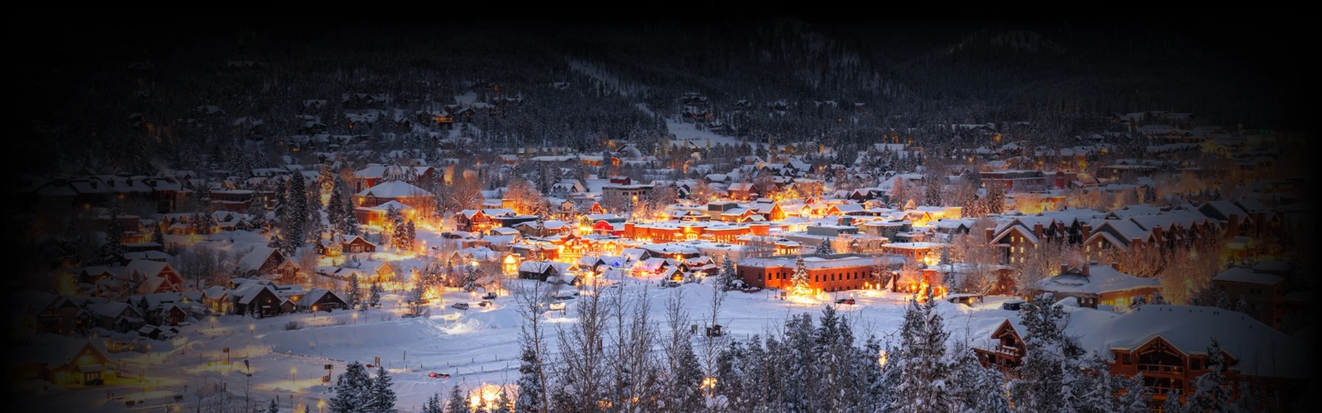 Snow-covered mountain town glowing with warm lights at dusk—capturing the magical winter scenery along the Denver to Breckenridge route, perfect for a luxury ski getaway.